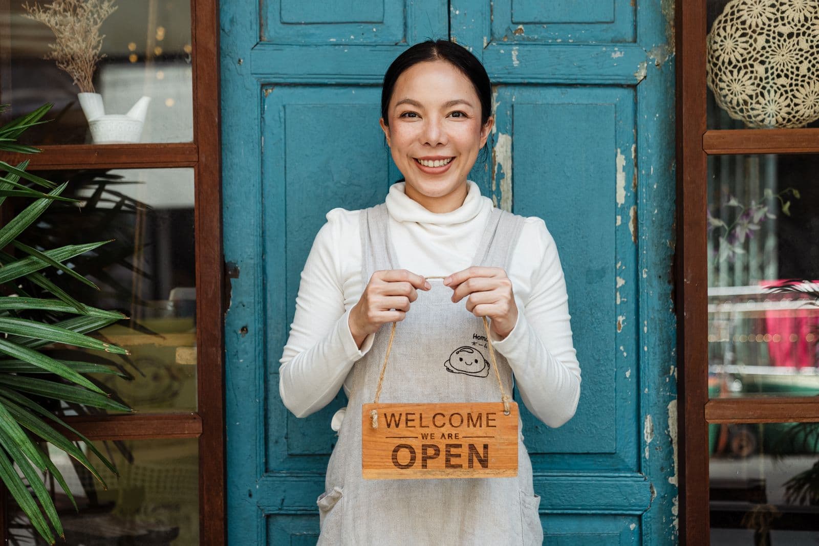 A small-business owner holding an OPEN sign
